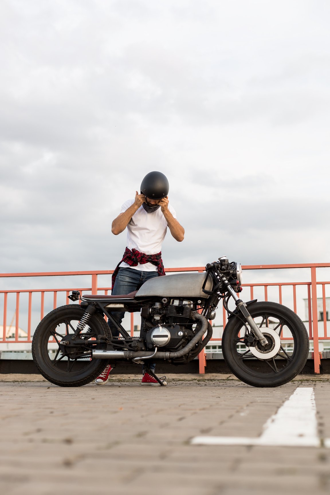 Brutal man near his cafe racer custom motorbike.